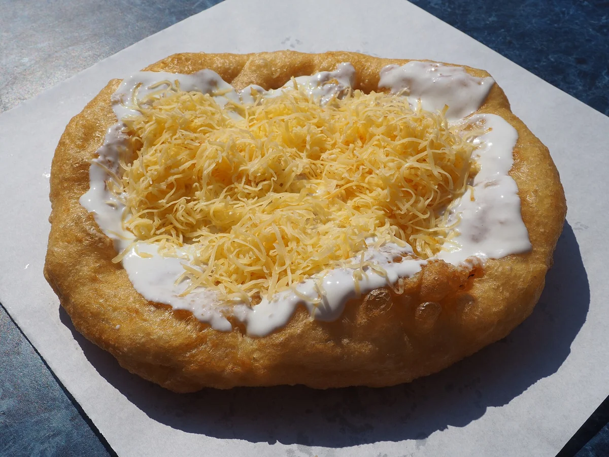 Lángos with sour cream and cheese, a savoury dish next to the Budapest chimney cake at the markets