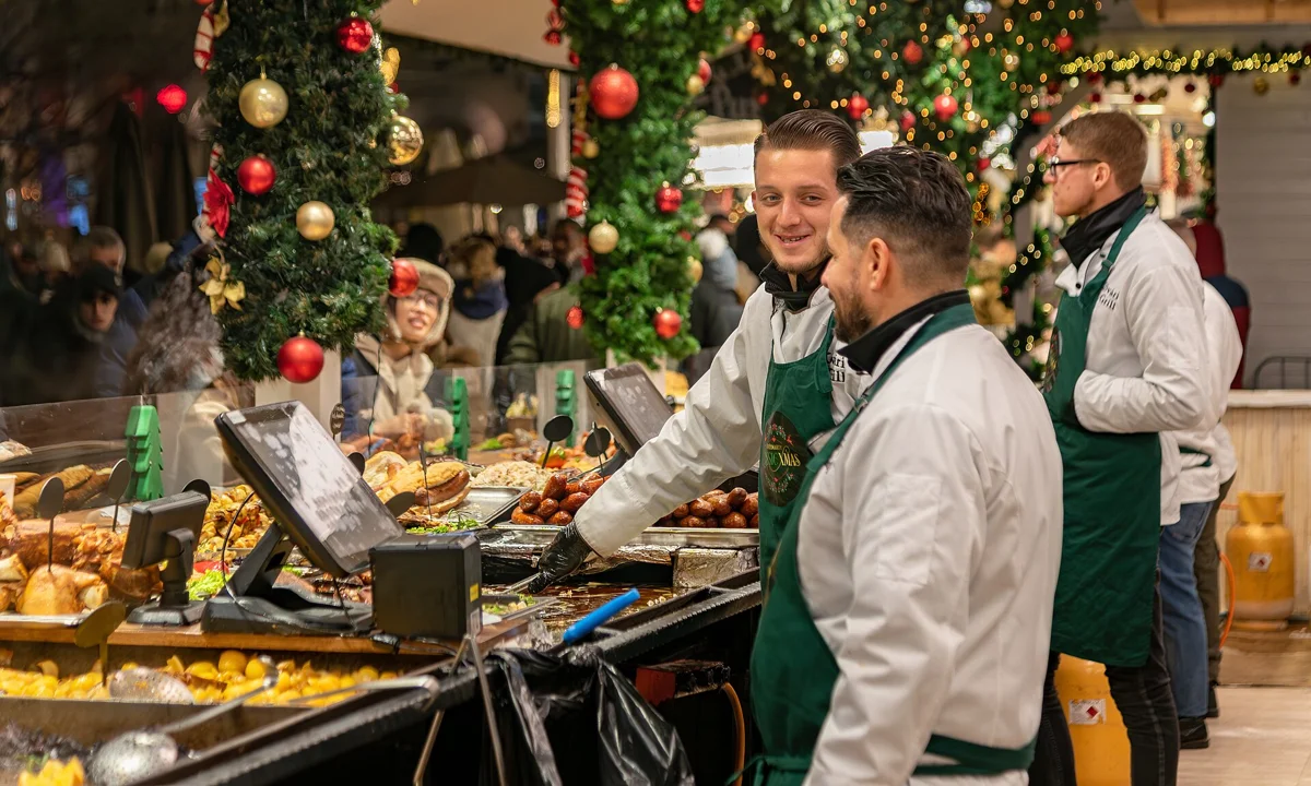 Cooks at a food stall at a Budapest Christmas market, the kind of stop on a Christmas market walking tour
